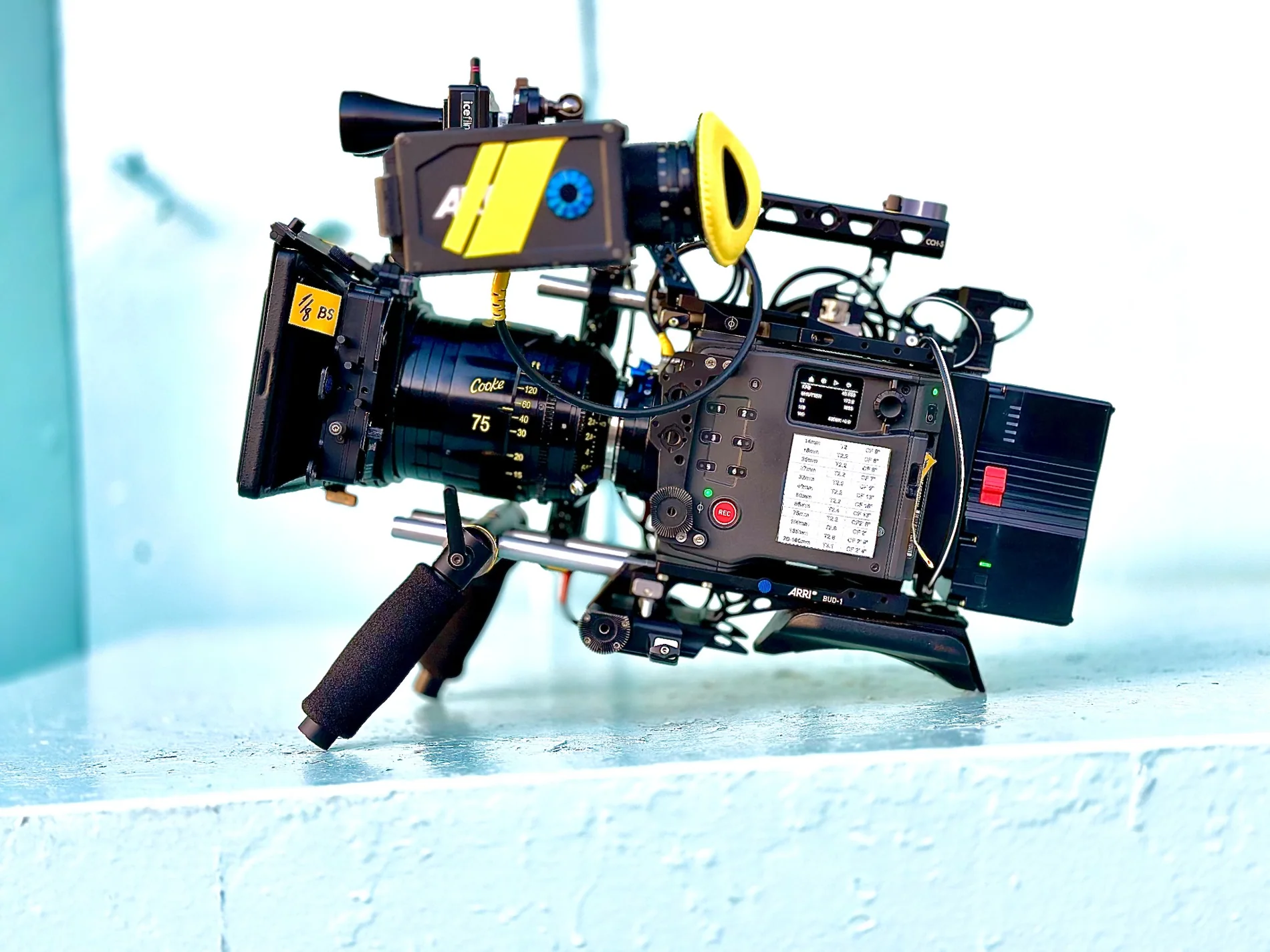 Cinema camera and lens photographed against a pale blue background