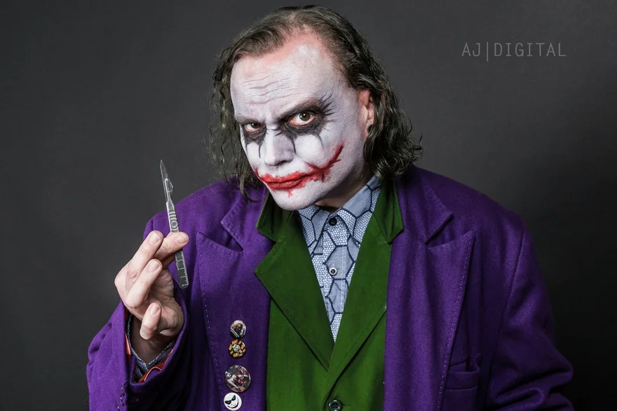 Studio portrait with theatrical face paint and a purple jacket against a grey background