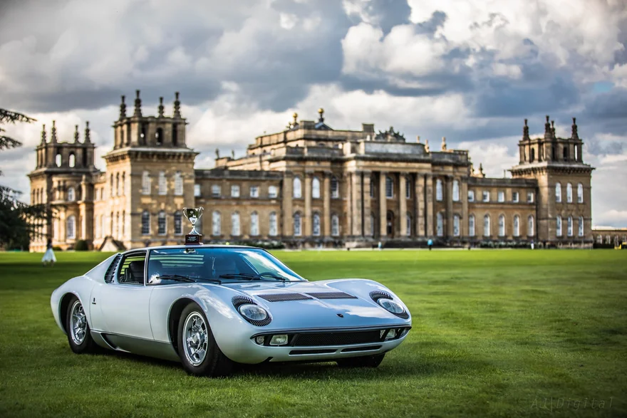 Silver classic sports car on the lawn in front of a large country house