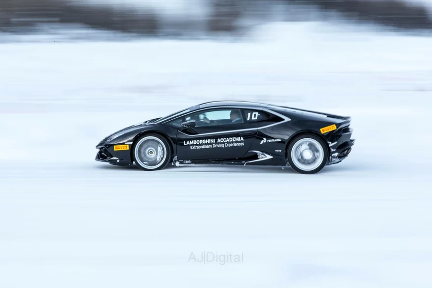 Panning photograph of a black sports car driving across snow
